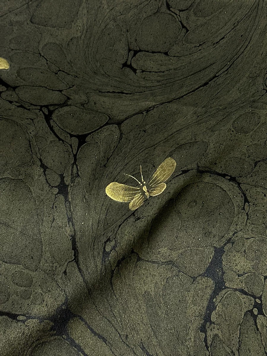 a golden butterfly resting on a marble-like surface.