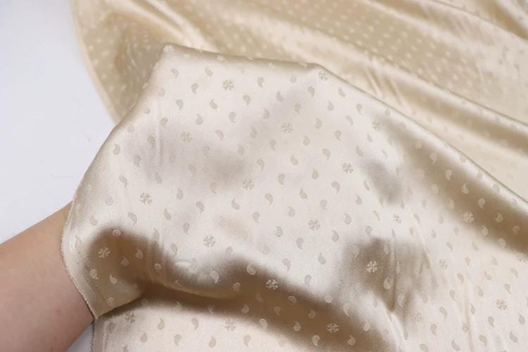 A close-up view of a piece of fabric with a repeating pattern of small white dots or flowers, creating a textured and visually interesting surface.