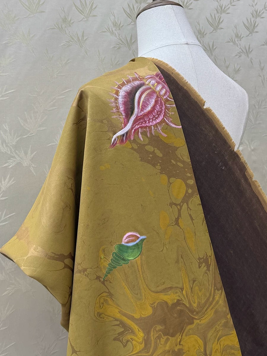 a mannequin wearing a vibrant, marbled fabric with a bird design. The fabric has a mix of yellow, brown, and green colors, creating a visually striking pattern.
