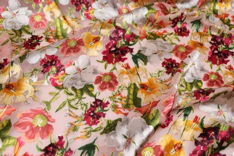 The image is a close-up view of a fabric with a vibrant floral pattern. The fabric is adorned with a variety of colorful flowers, including red, white, yellow, and green, creating a visually striking and lively design. The flowers are arranged in a way that fills the entire fabric, showcasing the intricate details and textures of the floral pattern.