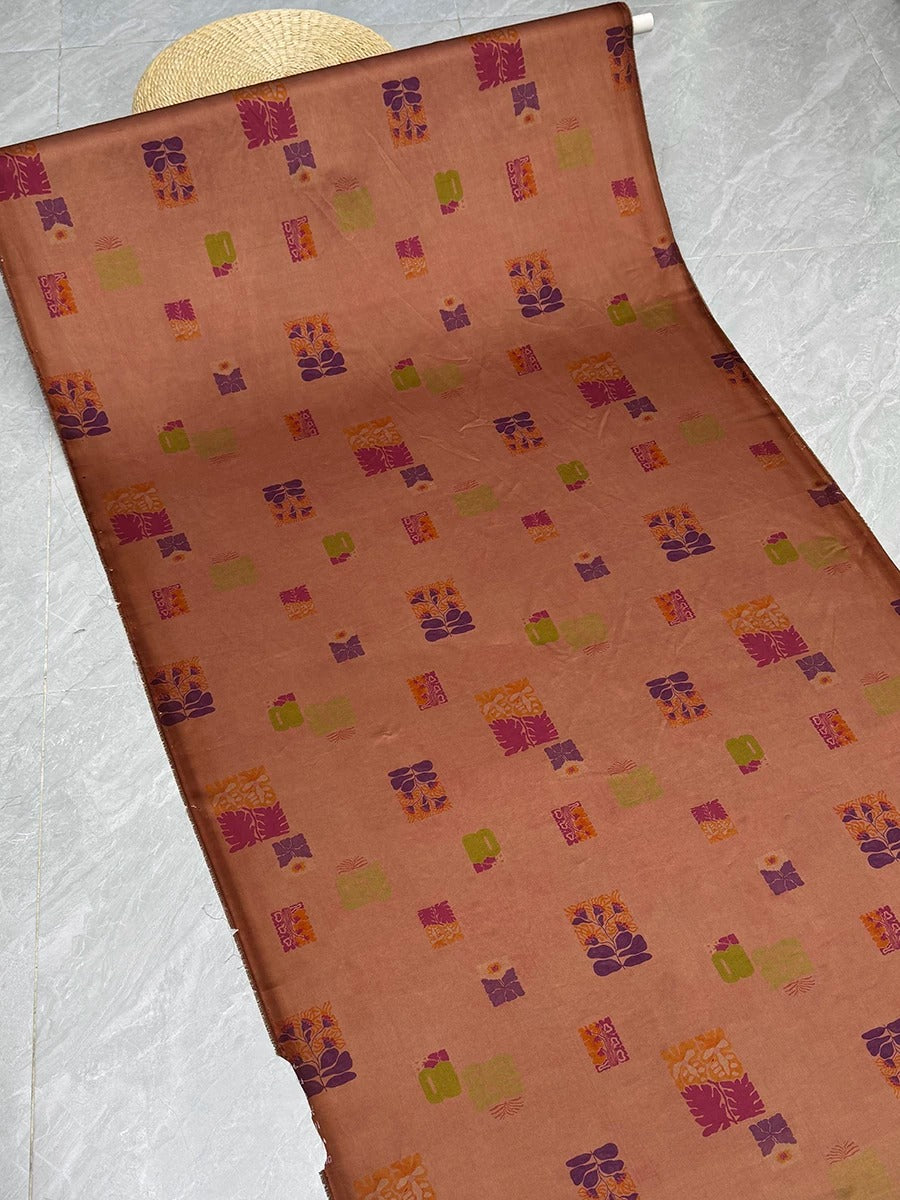 a roll of fabric with a repeating pattern of colorful squares and rectangles in shades of orange, purple, and green.