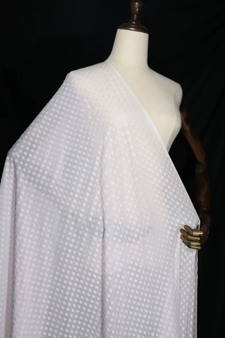 A mannequin wearing a white fabric with a polka dot pattern.