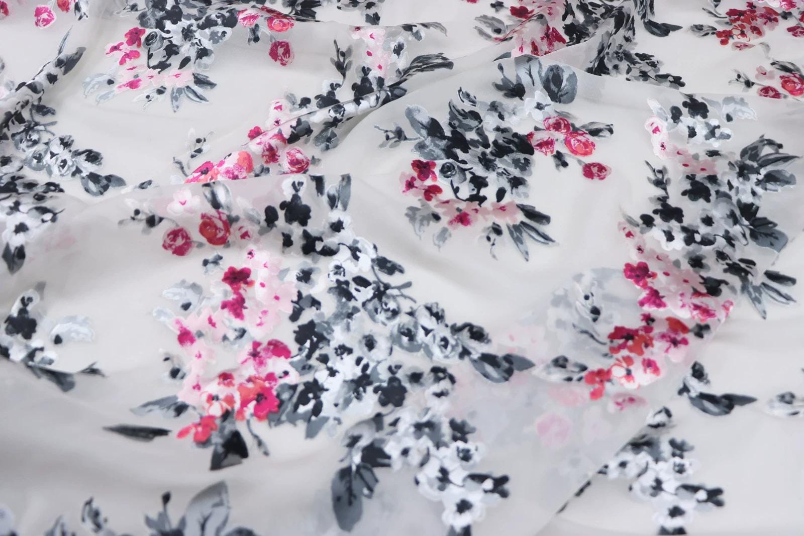 a close-up view of a fabric with a floral pattern in shades of pink, black, and white.