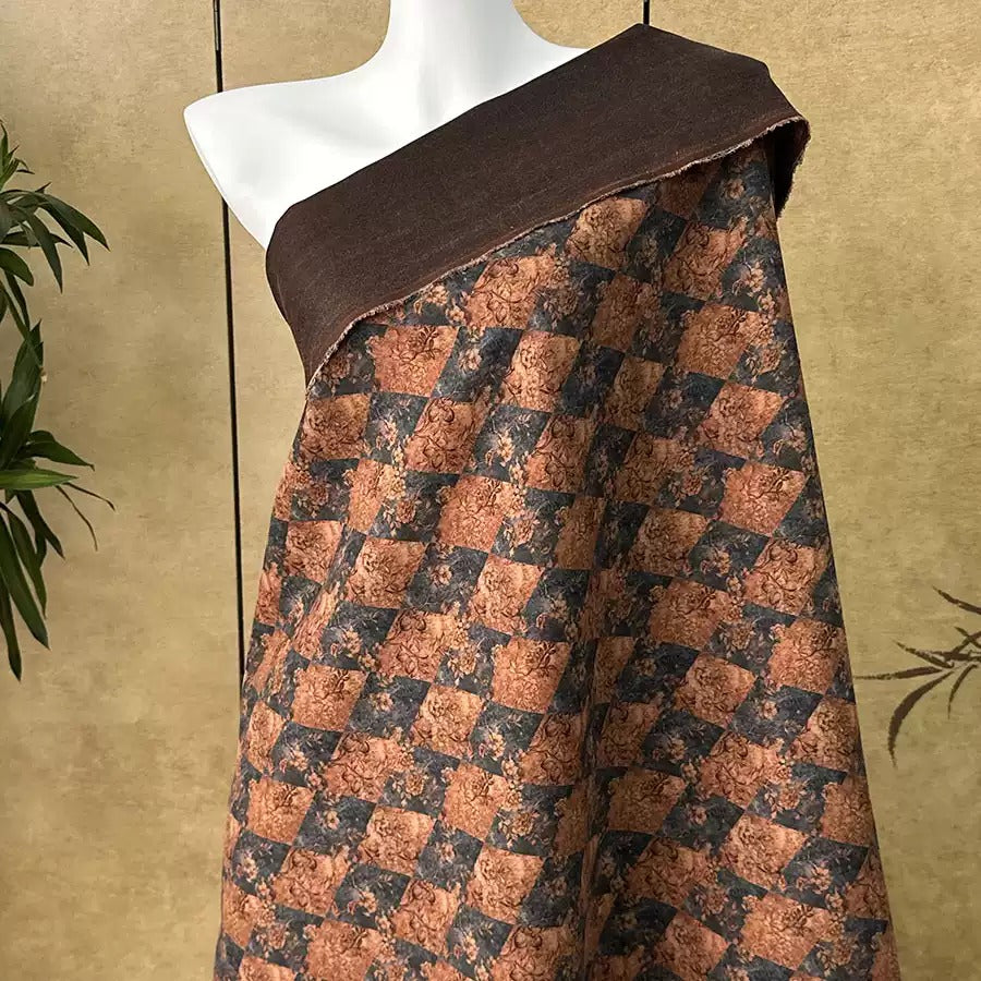 a mannequin wearing a brown and black patterned fabric draped over its shoulder.