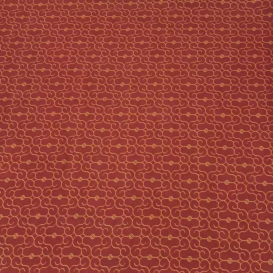 a repeating pattern of red and gold swirls on a fabric surface.
