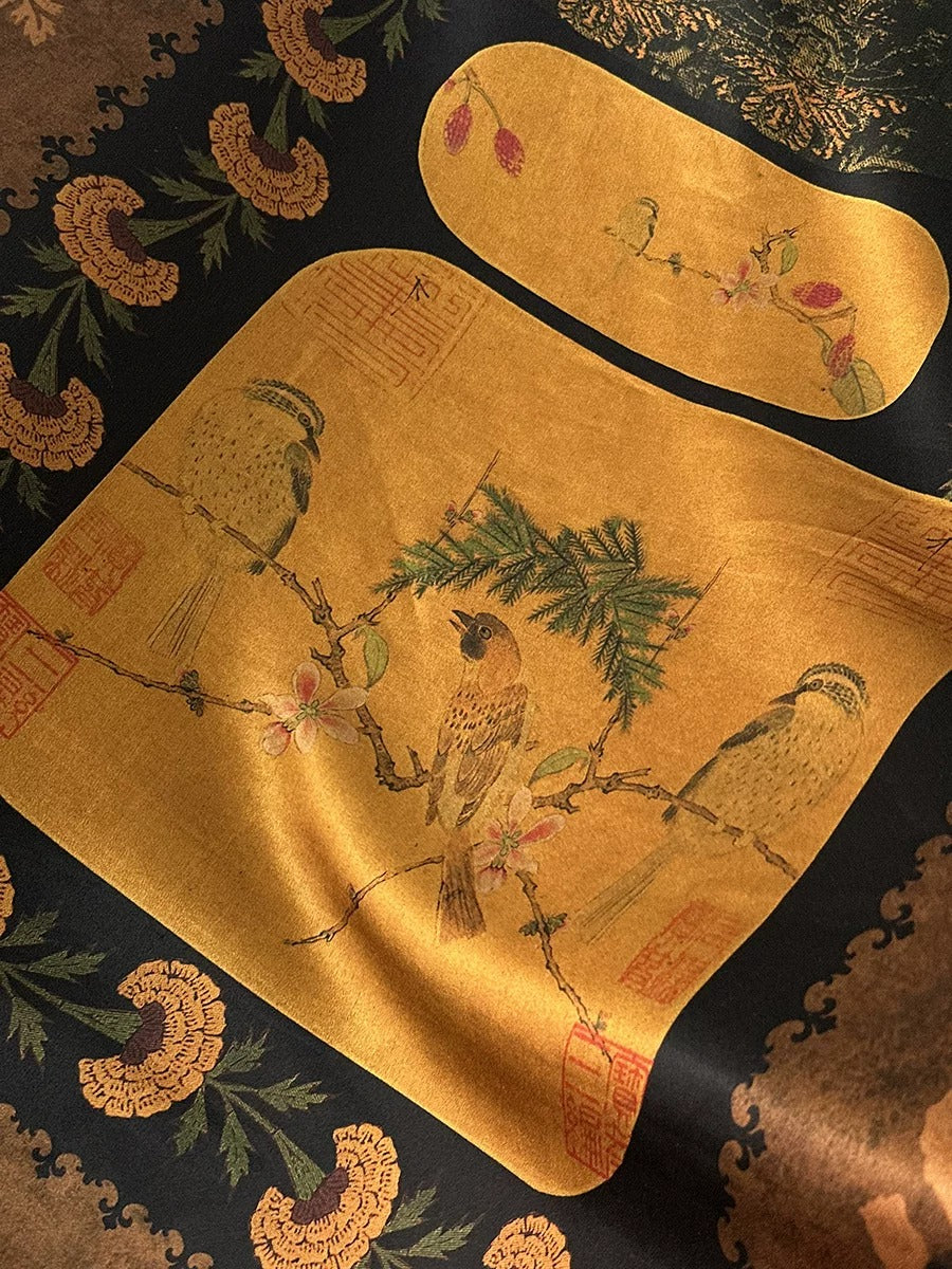 a close-up view of a decorative fabric with a gold-colored background and a detailed illustration of birds perched on branches. The fabric appears to be a piece of clothing or textile, with the intricate design and vibrant colors creating a visually striking and artistic composition.