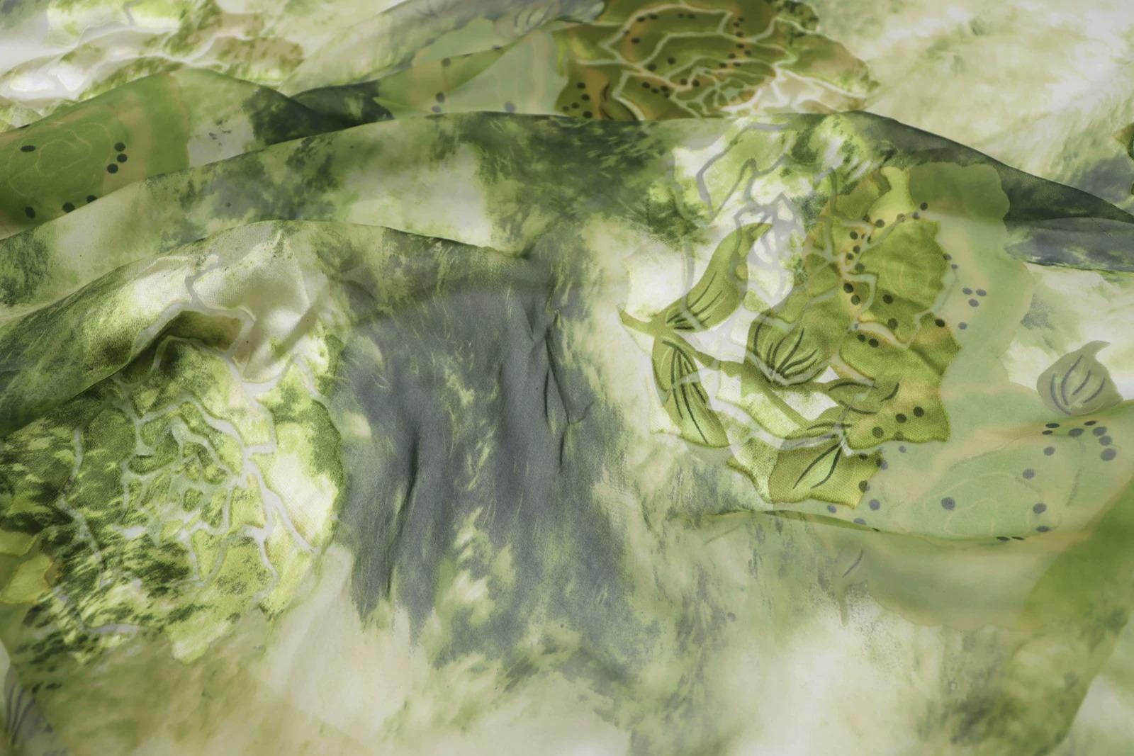 The image is a close-up of a fabric with a green and white pattern, featuring various shades of green and white, as well as some darker green and white elements.