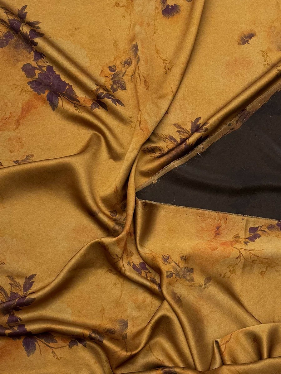 a close-up view of a fabric with a floral pattern in shades of gold and purple. The fabric appears to be crumpled and wrinkled, giving it a textured and soft appearance.