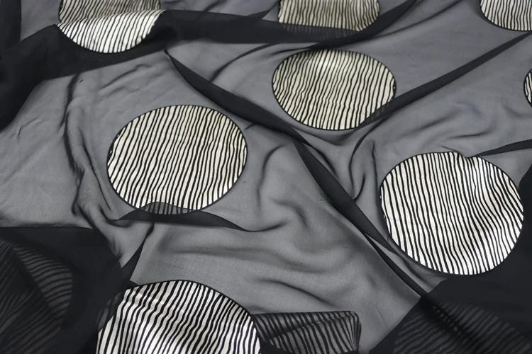 a close-up view of a fabric with a black and white striped pattern, featuring circular shapes with a zigzag design.