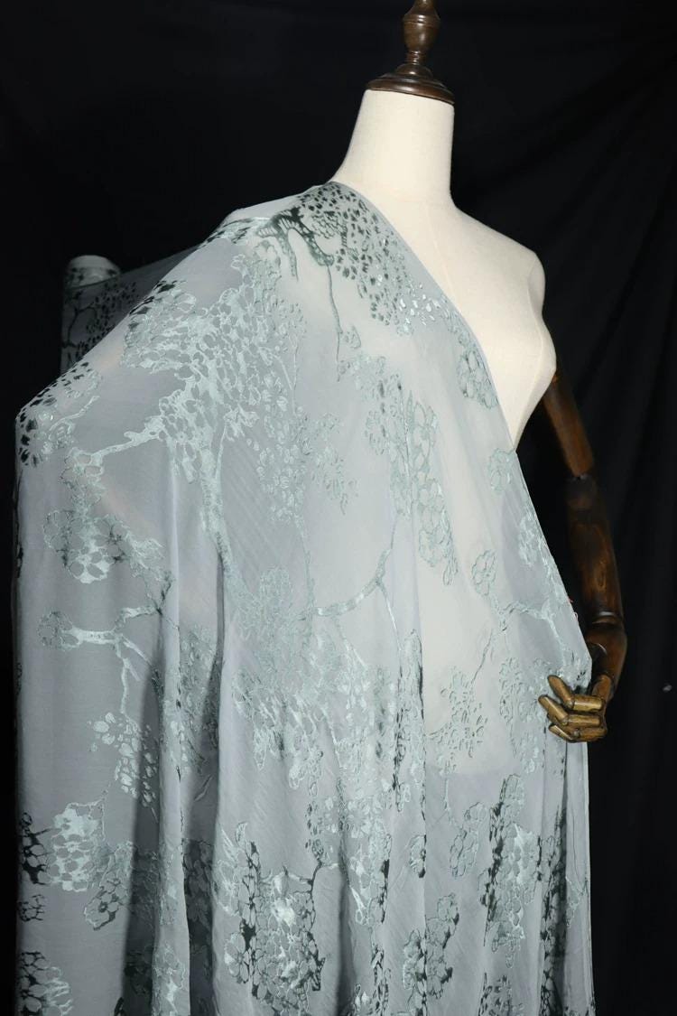 A mannequin wearing a light blue, sheer fabric with a floral pattern.