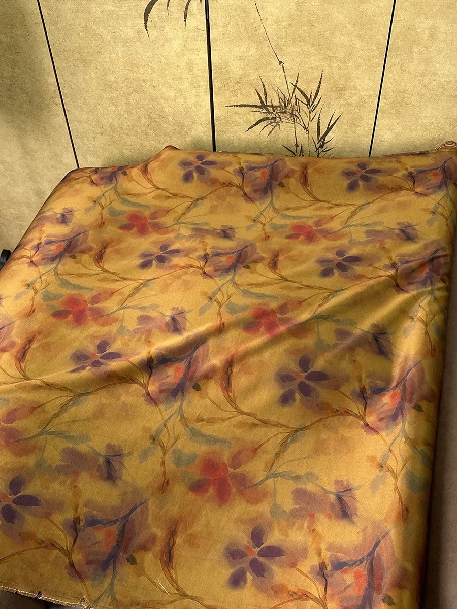 a bed with a floral print blanket, featuring a vibrant pattern of purple and orange flowers.