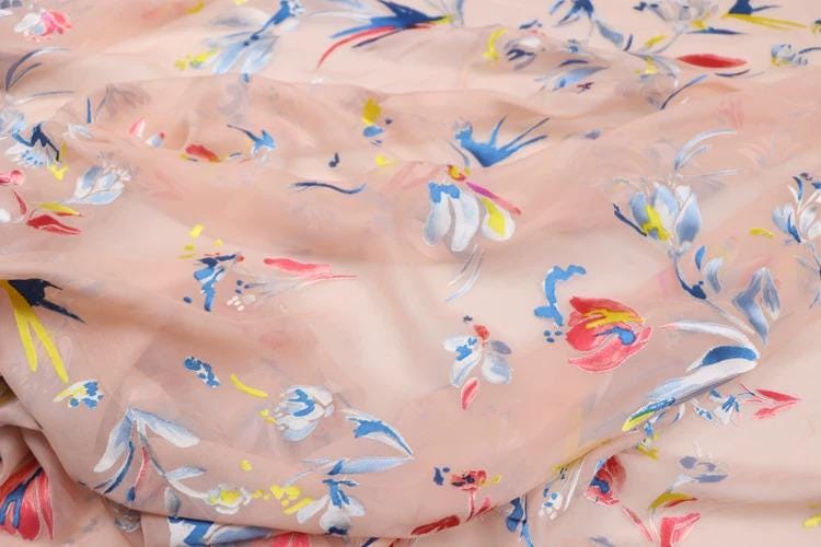 a close-up view of a fabric with a floral pattern in various colors, including pink, blue, and yellow.