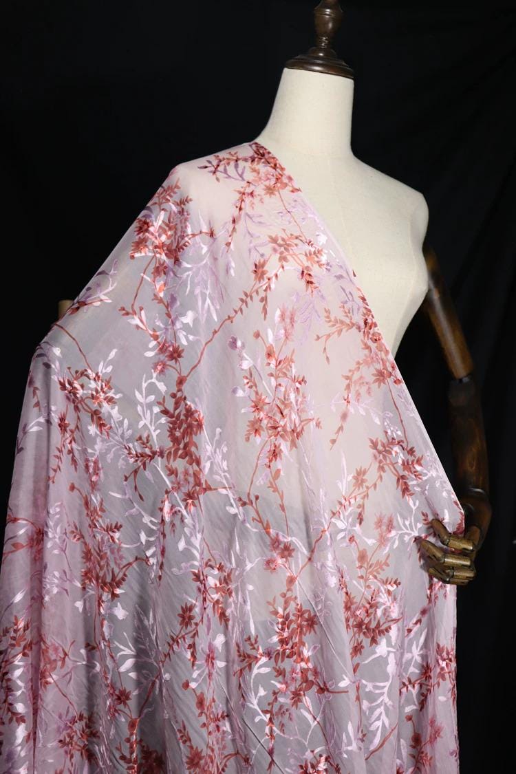 A mannequin wearing a white dress with a pink and red floral print draped over it.