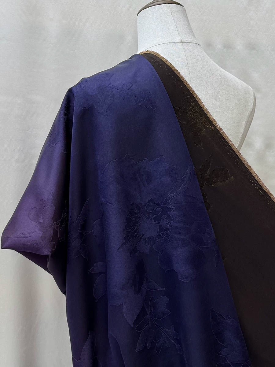 A mannequin wearing a purple and black fabric with a floral pattern.