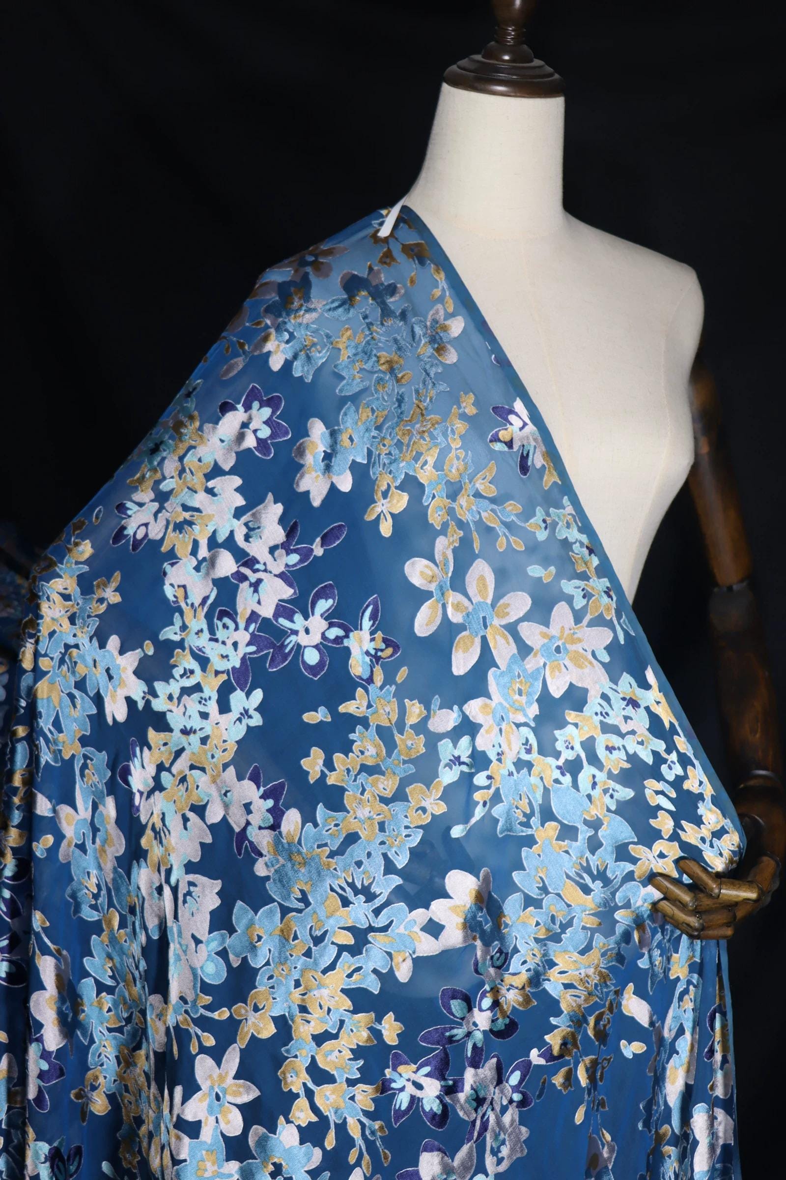 A mannequin wearing a blue and white floral print fabric draped over its body.