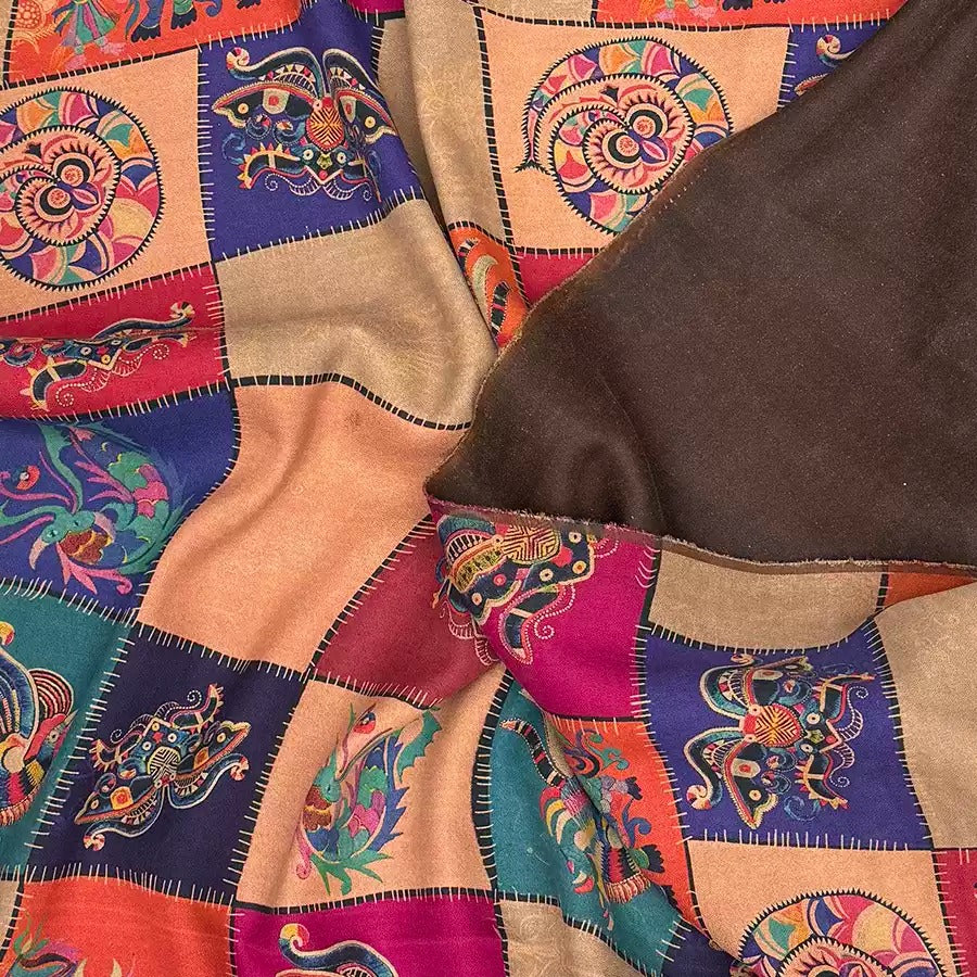 The image is a close-up of a colorful, patterned fabric with a mix of geometric and floral designs. The fabric appears to be a shawl or blanket, with a dark brown or brown-colored fabric visible on the right side.