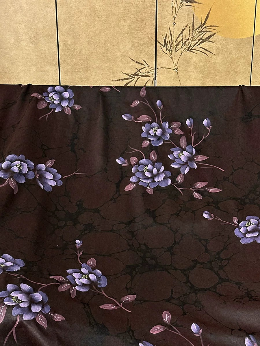 a dark brown fabric with a floral pattern of purple flowers and leaves.