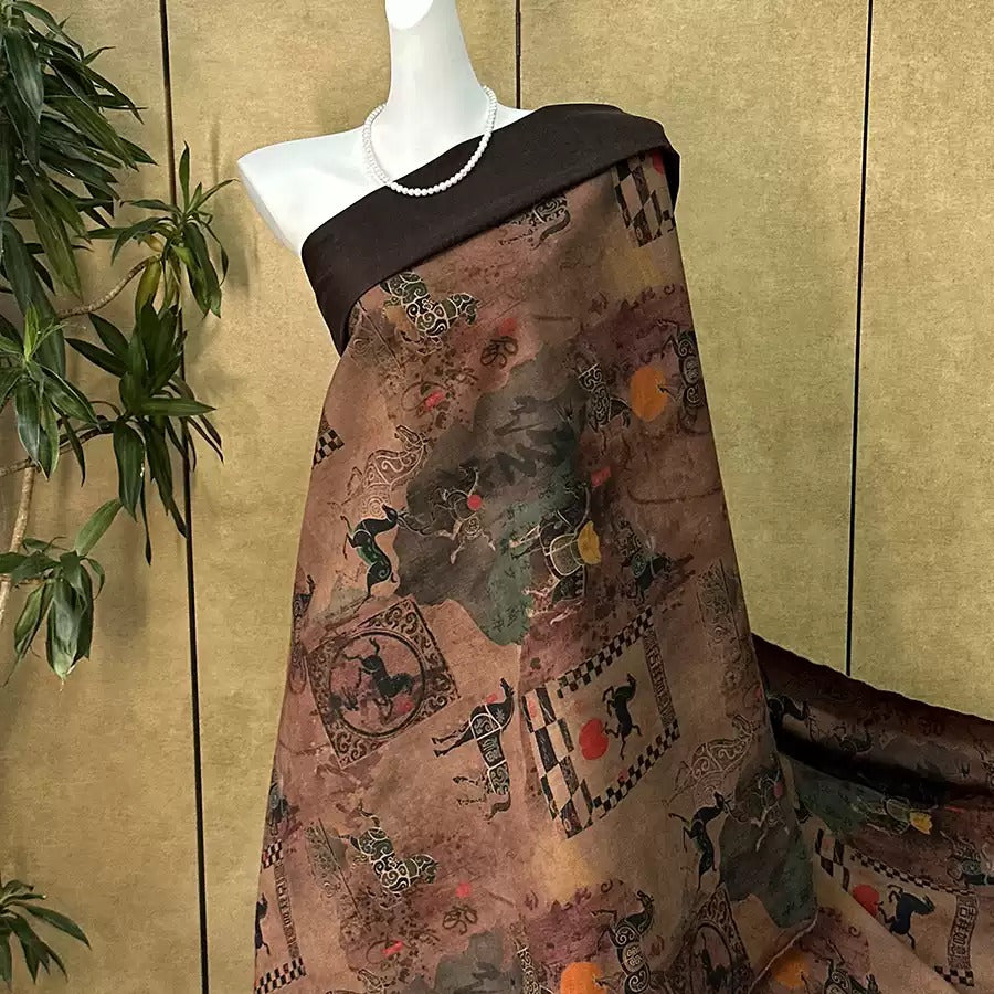 A mannequin wearing a brown fabric with a pattern of various animals and geometric shapes, displayed against a beige wall with a plant in the background.