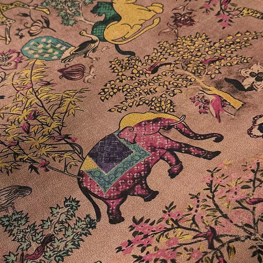 The image is a close-up of a vibrant, colorful fabric with a pattern of various animals, including elephants, birds, and flowers. The fabric appears to be a piece of embroidered or printed material, with a rich, warm color palette that includes shades of pink, yellow, green, and blue. The intricate details and patterns on the fabric create a visually striking and detailed image.