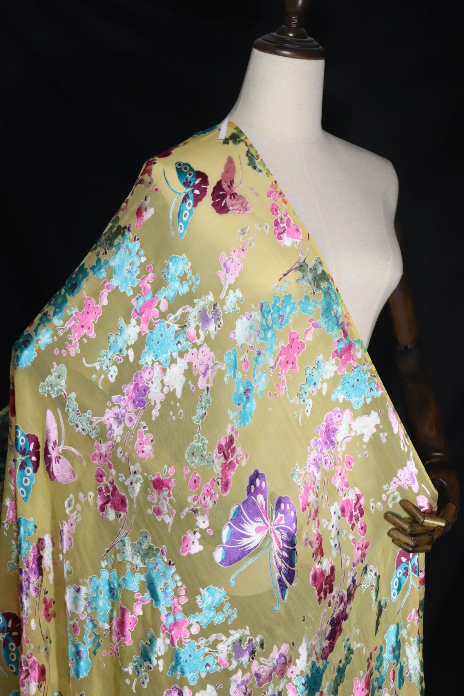 A mannequin wearing a yellow fabric with a floral print and colorful butterflies.