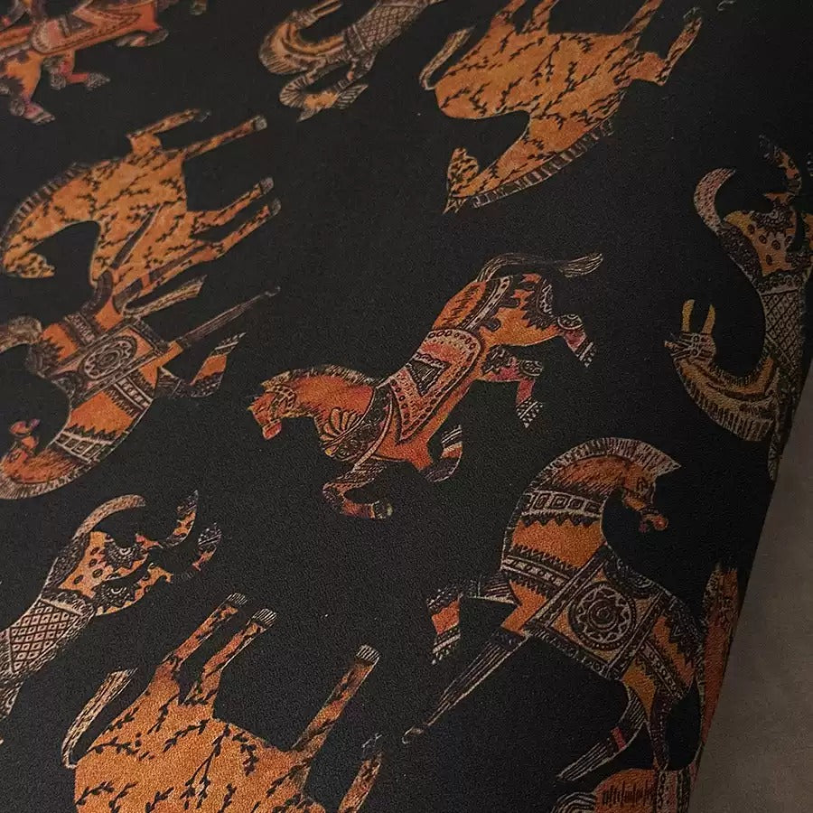 a close-up view of a black fabric with a repeating pattern of stylized animal designs, including horses, elephants, and other animals.