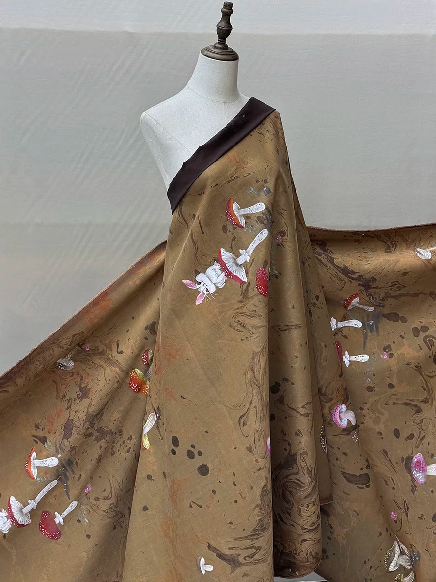 A mannequin wearing a brown fabric with a pattern of mushrooms and other organic shapes.