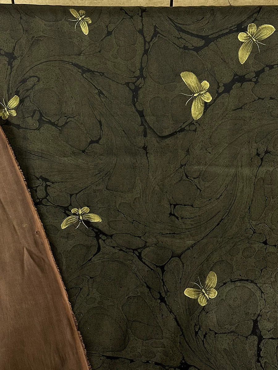 a close-up view of a dark green marble-like surface with gold butterflies scattered across it.
