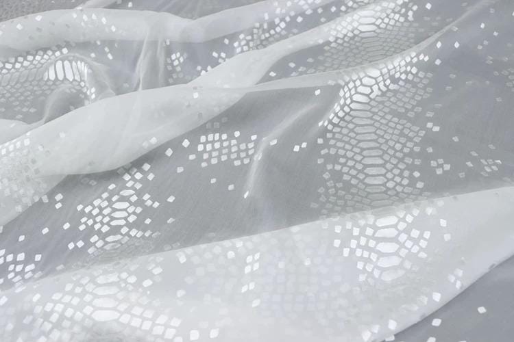 a close-up view of a white fabric with a pattern of small white squares or diamonds, creating a textured and visually interesting surface.