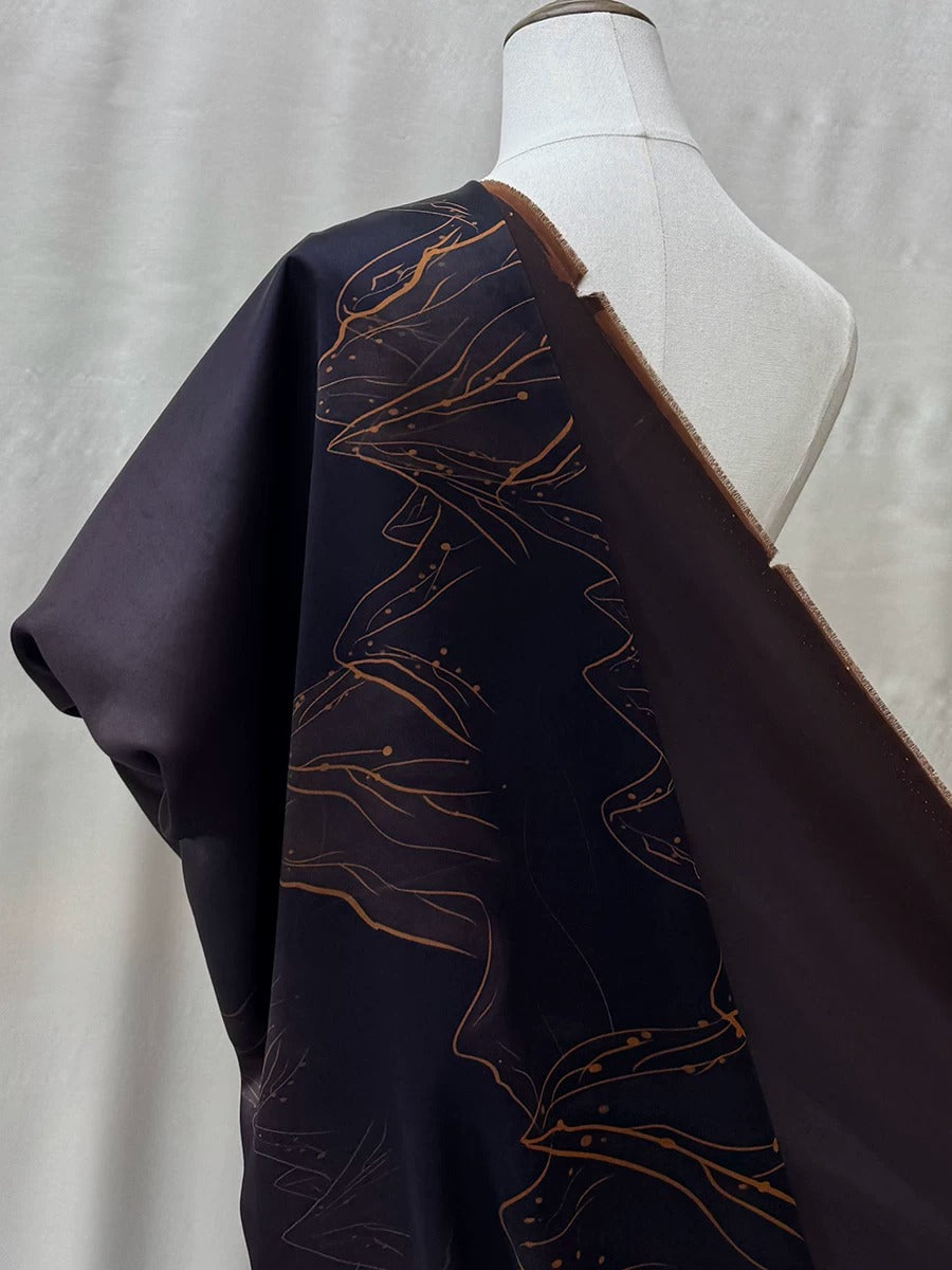 a mannequin wearing a dark blue fabric with a gold leaf pattern.