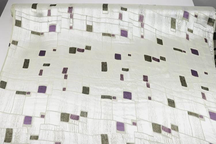 a white fabric with a pattern of purple and gray squares and rectangles.