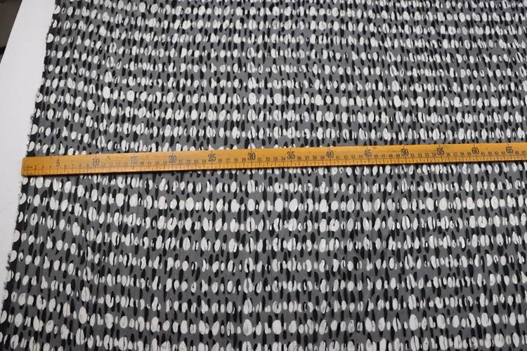 a close-up view of a fabric with a black and white pattern, and a ruler is placed across it, indicating the size or dimensions of the fabric.