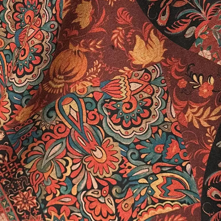 The image is a close-up of a vibrant, colorful fabric with intricate patterns and designs. The fabric appears to be a paisley pattern, featuring a mix of red, orange, yellow, and green colors. The patterns are detailed and detailed, showcasing the craftsmanship and artistry of the fabric.