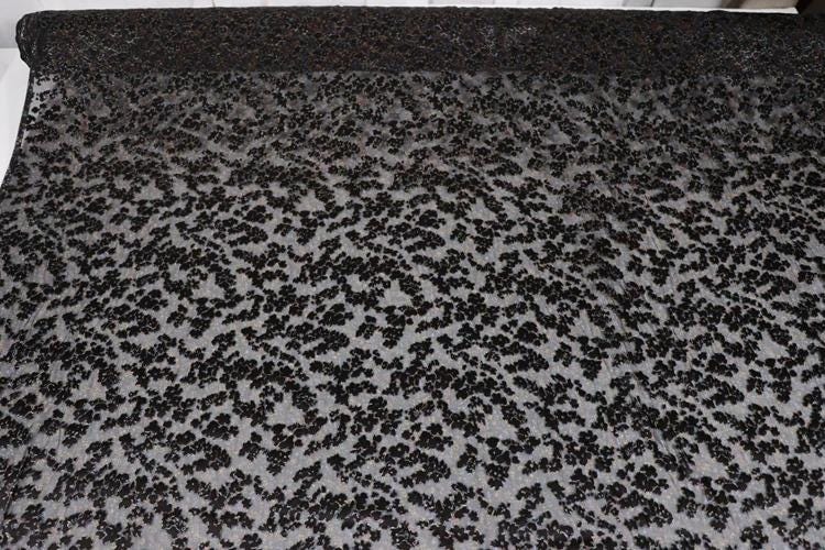 a close-up view of a black fabric with a pattern of small black dots or specks covering the entire surface.