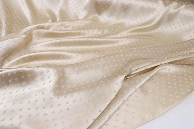 a close-up view of a fabric with a light beige color and small white dots or circles on it.
