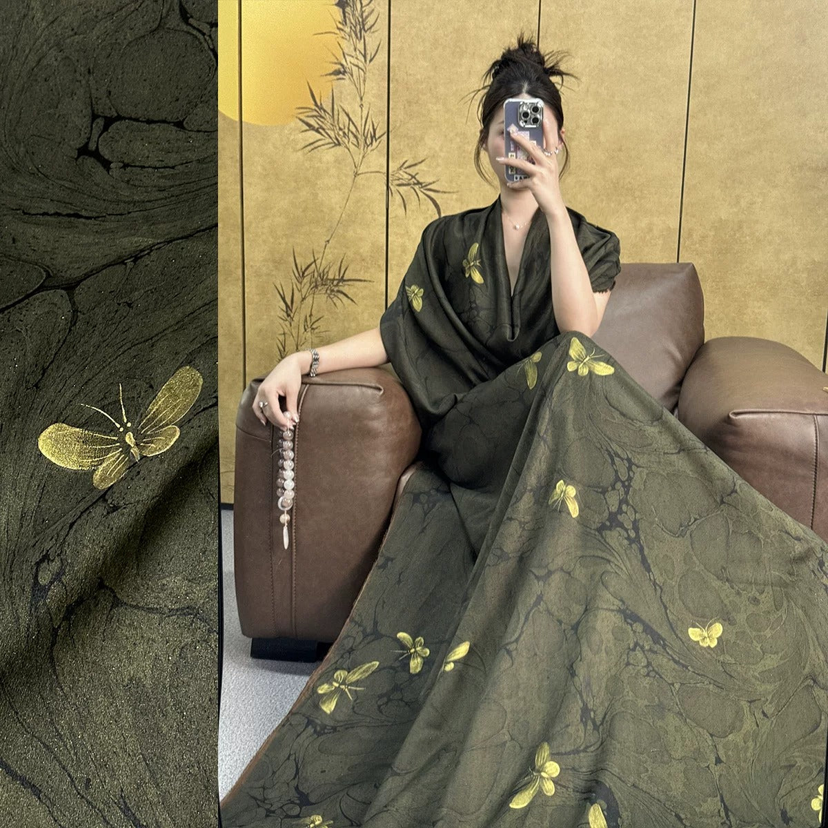A woman is sitting on a brown leather couch, holding a silver necklace and wearing a green dress with yellow butterfly designs.