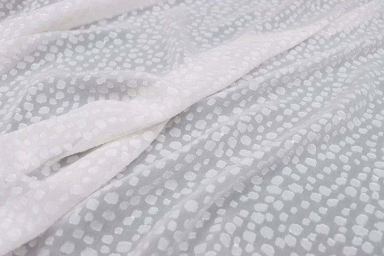 a close-up view of a white fabric with a pattern of small white dots or circles on it.