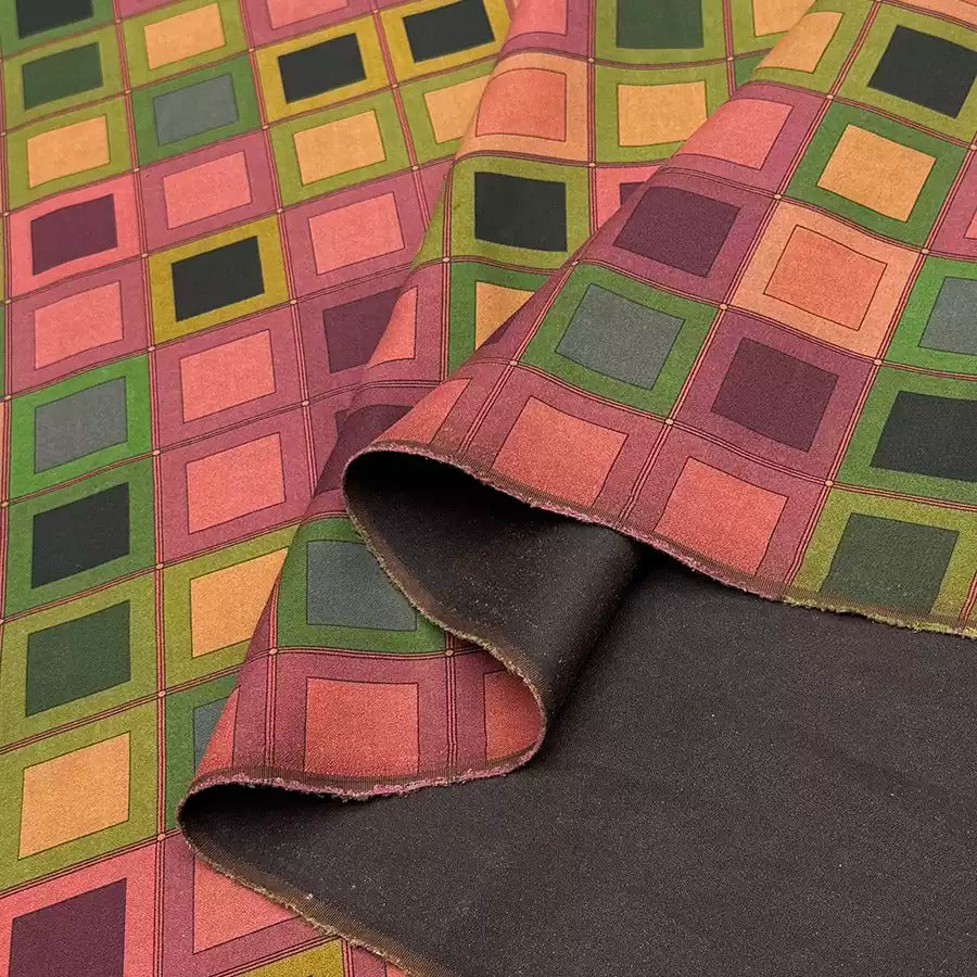 a vibrant, colorful fabric with a geometric pattern of squares in various shades of green, red, and orange.
