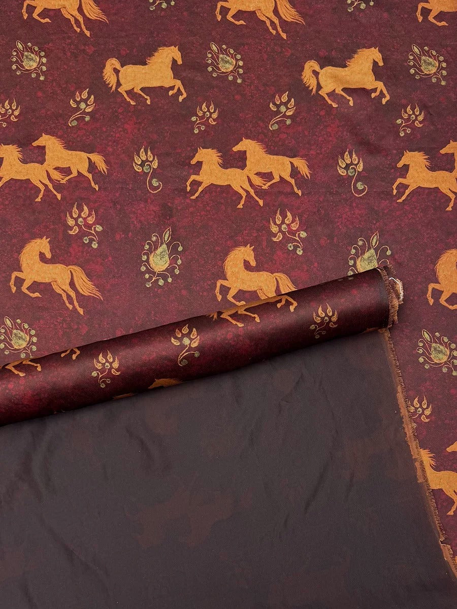 a maroon fabric with a repeating pattern of gold horses and leaves. The horses are depicted in various poses, creating a dynamic and lively design. The fabric appears to be rolled up and displayed, showcasing the intricate pattern and design.