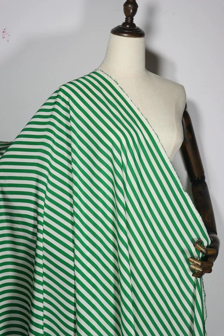 A mannequin wearing a green and white striped fabric draped over its body.