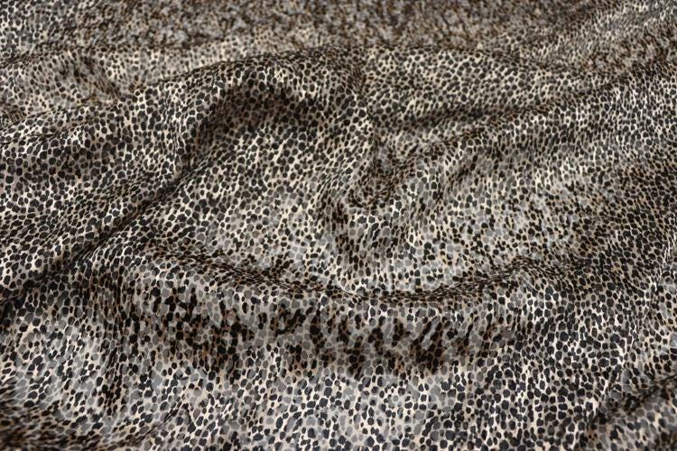 a close-up view of a fabric with a distinctive leopard print pattern. The fabric appears to be made of a material with a textured, spotted appearance, resembling the fur of a leopard.