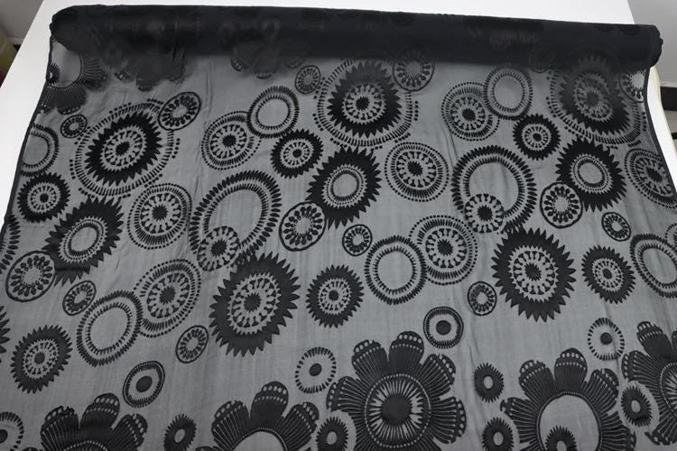 a black and white fabric with a repeating pattern of circular designs.
