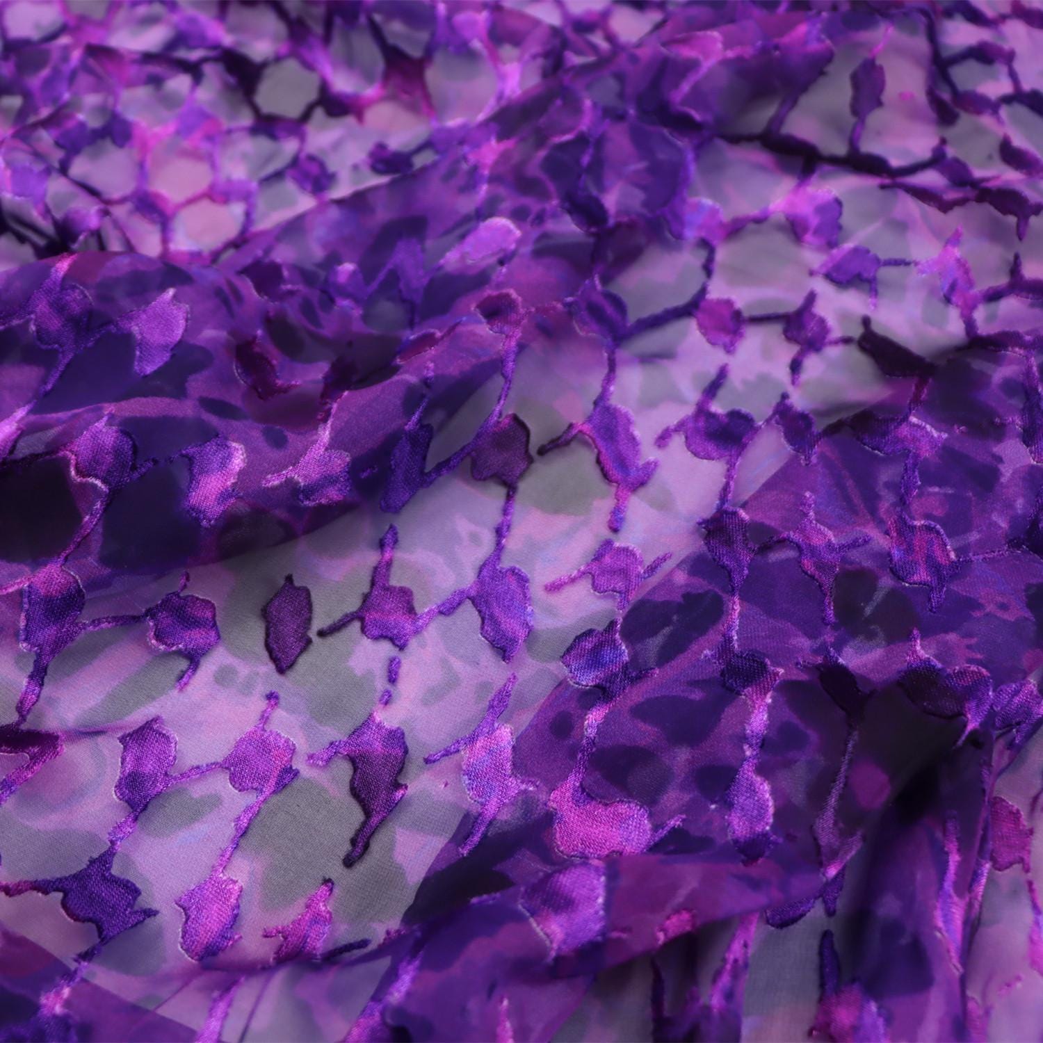 a close-up view of a fabric with a purple and gray pattern, featuring a repeating geometric design.