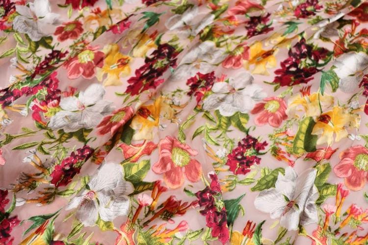 The image is a close-up of a fabric with a vibrant floral pattern, featuring a variety of colorful flowers and leaves.