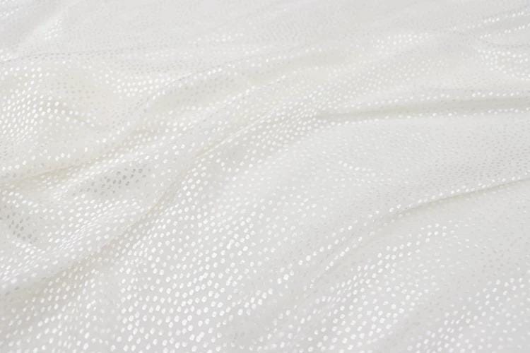 a close-up view of a white fabric with small white dots or polka dots, creating a textured and shiny appearance.