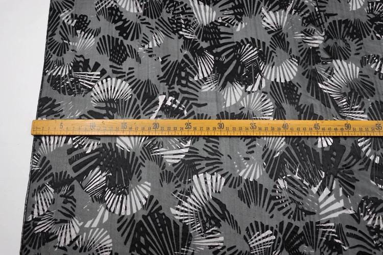 a close-up view of a fabric with a black and white pattern, with a yellow measuring tape placed across it, indicating the size or dimensions of the fabric.