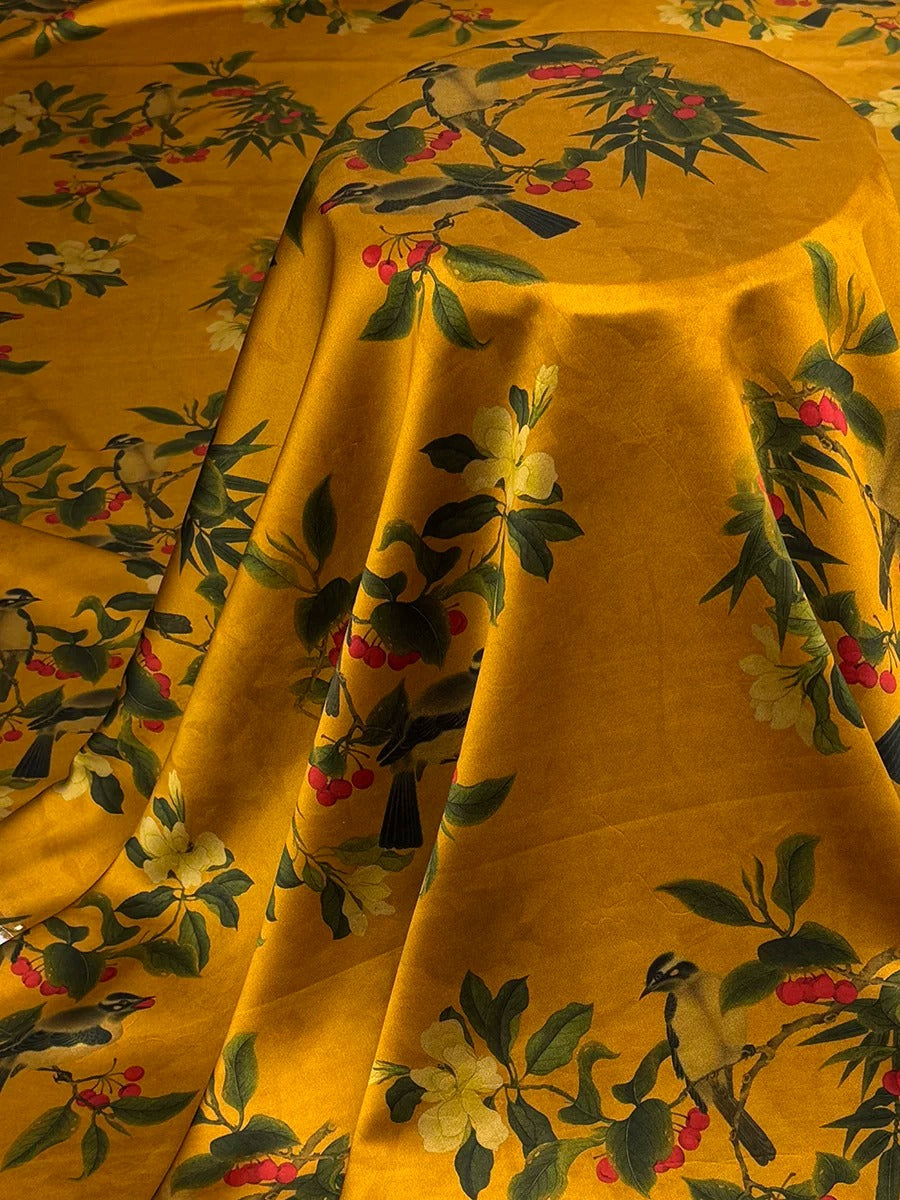 a vibrant yellow fabric with a floral pattern, including birds and flowers, creating a lively and colorful design.