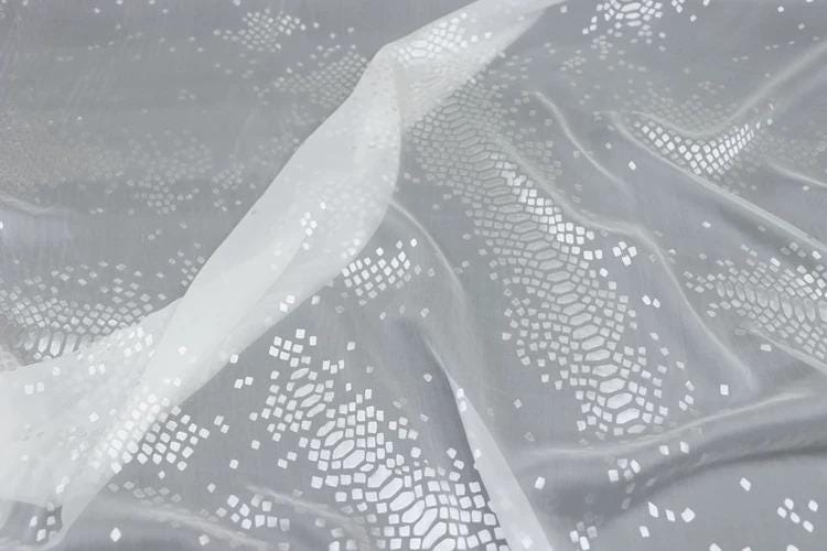 a close-up view of a white fabric with a pattern of small white dots or shapes, creating a textured and visually interesting surface.