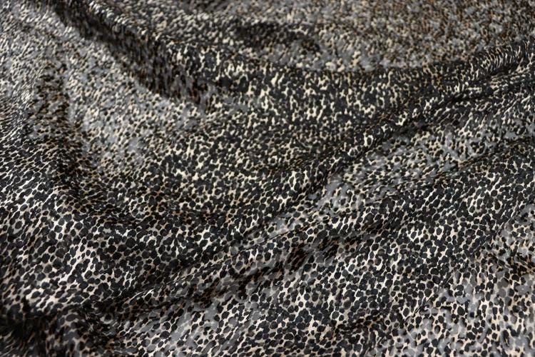 a close-up view of a fabric with a distinctive leopard print pattern. The fabric appears to be a blend of black and white colors, with the leopard print pattern adding a touch of contrast and visual interest to the overall design.