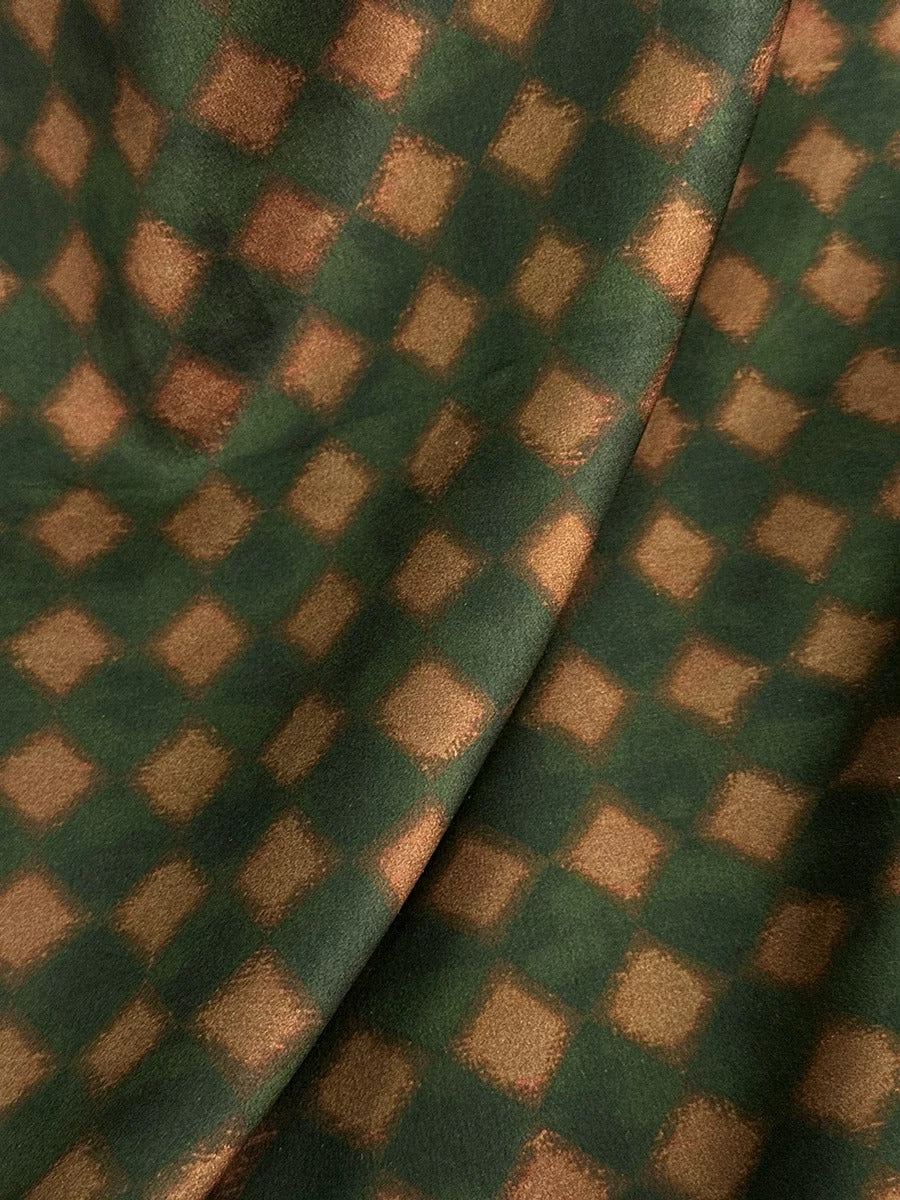 a close-up view of a fabric with a repeating pattern of green and brown squares, creating a visually interesting and textured design.