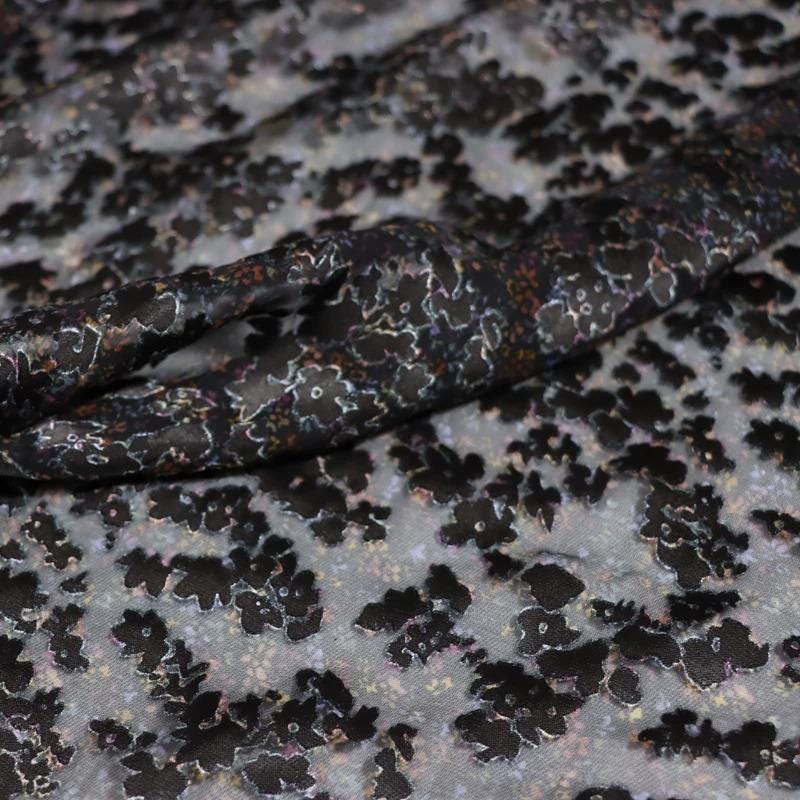 a close-up view of a fabric with a floral pattern, featuring a mix of black and gray colors.